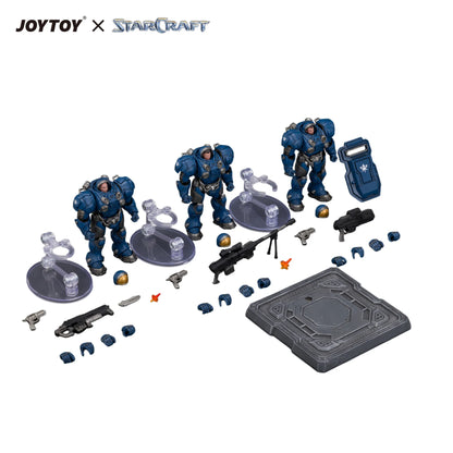 JOYTOY x StarCraft sci-fi action figure set on a white background, including three blue armored space marine figures with accessories such as weapons, clear stands, a blue storage box, and a gray baseplate.